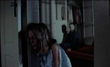 Jamie Lee Curtis as Laurie Strode, shown trotting away from serial killer Michael Meyers in Halloween.