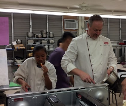 Executive Chef Ryan Day from Palama Meat Company guides culinary students with preparing watermelon poke, lemongrass chicken, kalua kale soup, shrimp with broccoli leaves, fresh corn, and kabocha and cantaloupe cupcakes. Culinary students visited Aloun Farms on Sept. 10, and returned to school with donated produce from the farm. “We got to see how the fruits and vegetables get started, and to see the difference between store bought and farm fresh,” culinary teacher Jamie Kahalewai said.