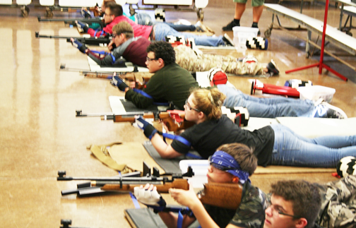 Air riflery members Sam Sharpe (10), Alexander Roynon (9), Kortni Baughman (10), Anthony Hewitt (10), David Pounds (12), Bailey Wells (12), and Alysa Wipperman (11) take on a prone position, where they lay on their stomach shooting 20 targets for 20 minutes during practice in the school cafeteria. Hawaii is one of 18 states this sport is offered to high school students. Photo by Alyssa Green