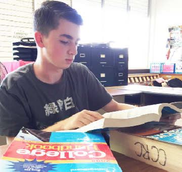 Matthew Mann (11) peruses through College and Major Handbooks during TASK. Two hundred two students took the PSAT during the fall break. “I feel the PSAT is the best method of practice to predict how one will do on the actual SAT,“ he said.