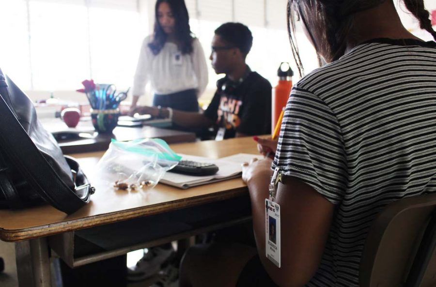 Jade Souza (12) makes sure her badge is clipped securely to her top,  Tyrique Clay (12) keeps it on a chain around his neck, and Moana Robinson (11) keeps it clipped to her sleeve. Students are required to wear their school identification badges on at all times during the school day. Photos by Cristian Torres